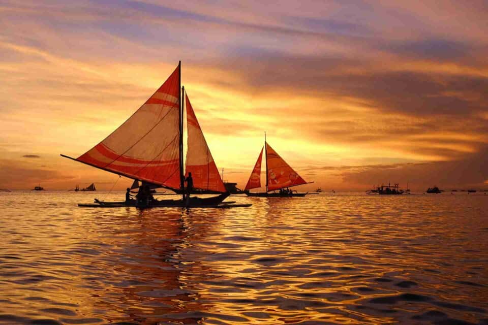 Red sailing boats on the sea captured in the moment of sunset